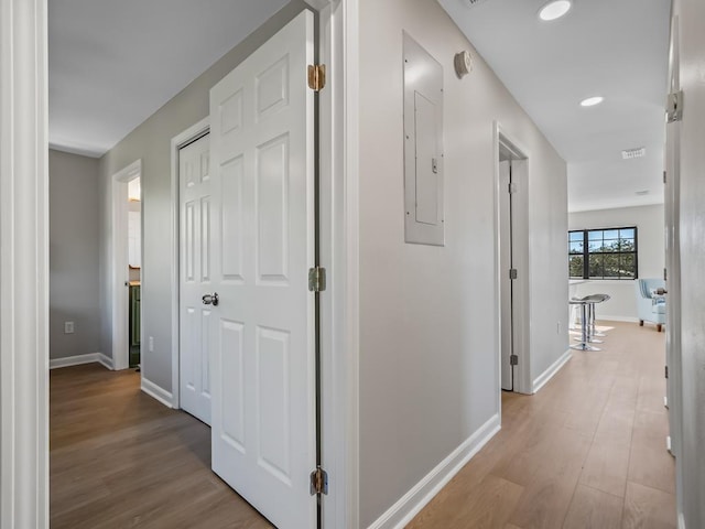 corridor with electric panel and light hardwood / wood-style flooring