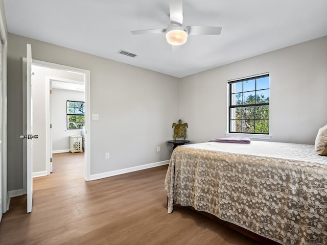 bedroom featuring ceiling fan, wood-type flooring, and multiple windows