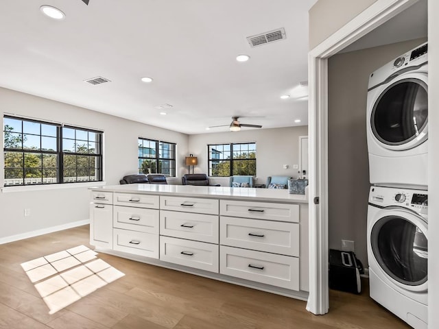 laundry room featuring light hardwood / wood-style floors, ceiling fan, and stacked washer / drying machine