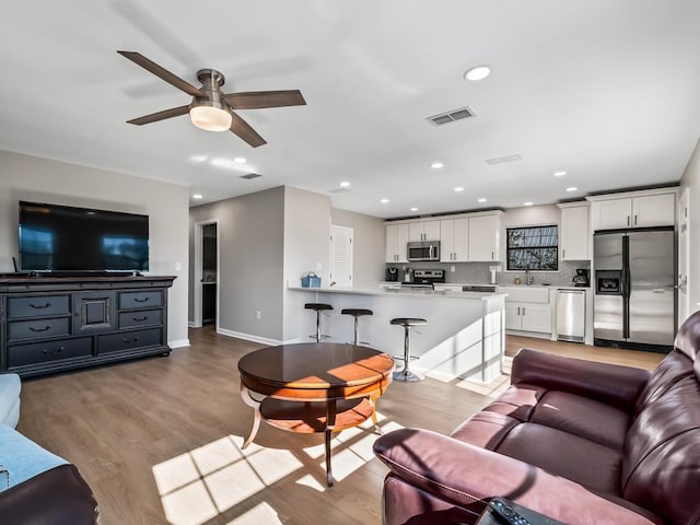 living room with ceiling fan, light hardwood / wood-style flooring, and sink