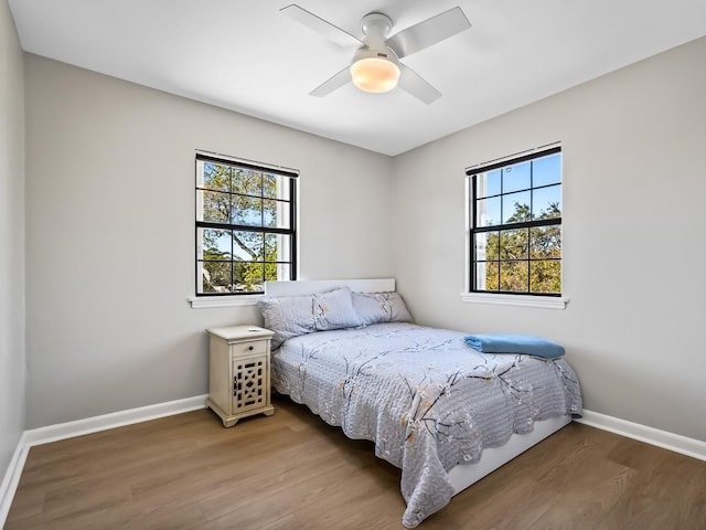 bedroom with multiple windows, ceiling fan, and hardwood / wood-style floors