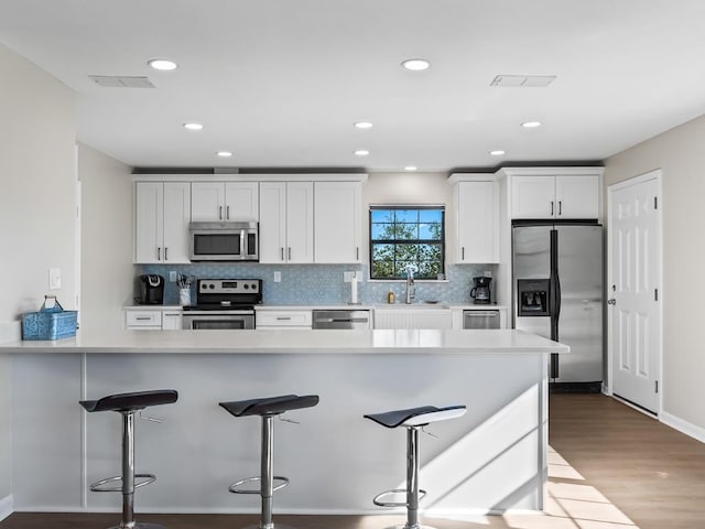 kitchen featuring white cabinetry, sink, stainless steel appliances, and light hardwood / wood-style floors