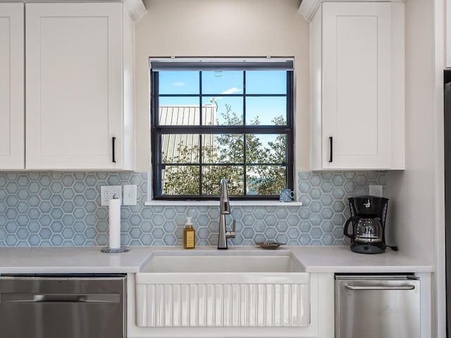 kitchen with stainless steel dishwasher, backsplash, white cabinets, and sink