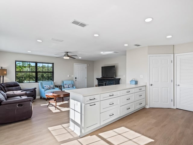 kitchen featuring kitchen peninsula, ceiling fan, white cabinets, and light wood-type flooring