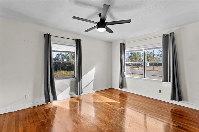 unfurnished room with wood-type flooring, a textured ceiling, ceiling fan, and a healthy amount of sunlight