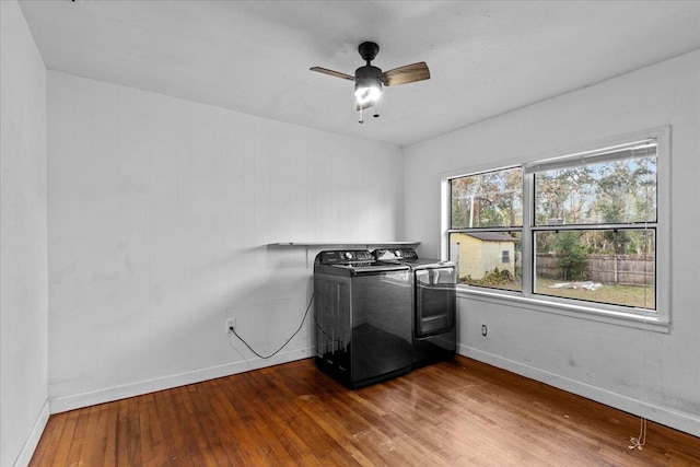 laundry area with washing machine and dryer, ceiling fan, wood-type flooring, and wood walls