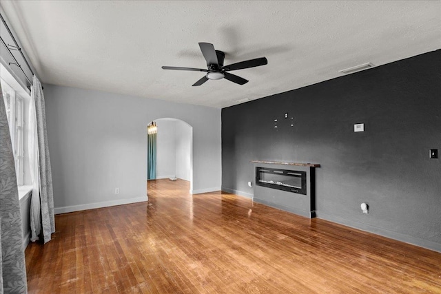 unfurnished living room with ceiling fan, wood-type flooring, and a textured ceiling