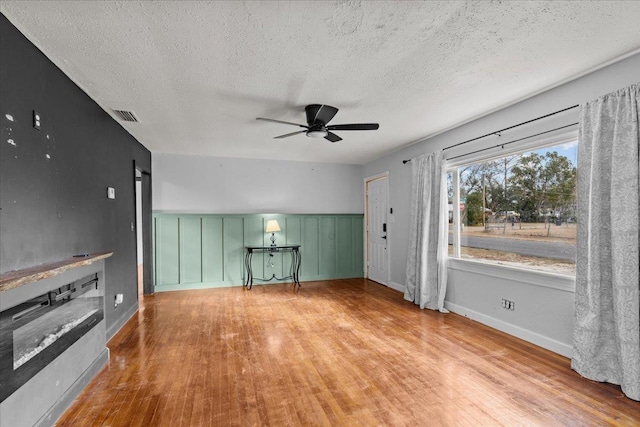 unfurnished living room featuring ceiling fan, light hardwood / wood-style floors, and a textured ceiling