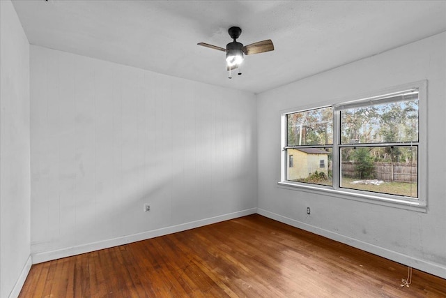 empty room with plenty of natural light, ceiling fan, and wood-type flooring