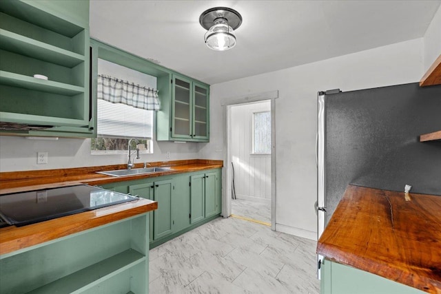 kitchen featuring butcher block counters, sink, green cabinets, and plenty of natural light