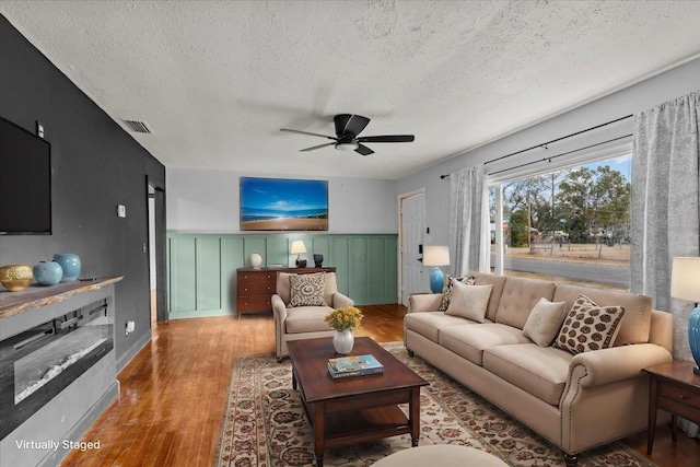 living room with ceiling fan, hardwood / wood-style floors, and a textured ceiling