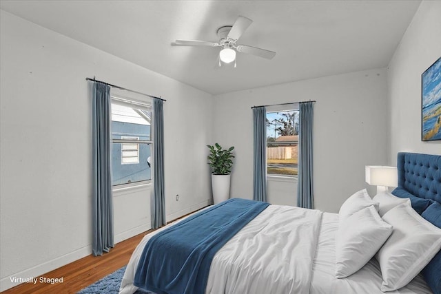 bedroom with hardwood / wood-style floors, multiple windows, and ceiling fan