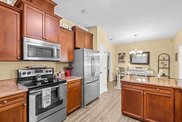 kitchen with an inviting chandelier, hanging light fixtures, light wood-type flooring, a textured ceiling, and appliances with stainless steel finishes