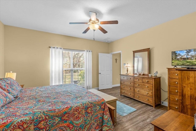 bedroom featuring ceiling fan, dark hardwood / wood-style flooring, and a textured ceiling