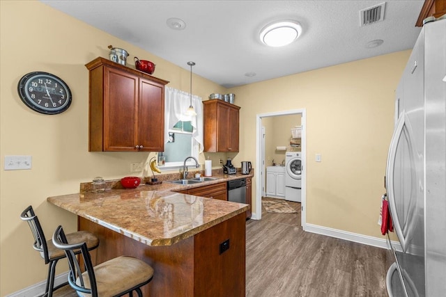 kitchen featuring kitchen peninsula, a kitchen bar, sink, wood-type flooring, and hanging light fixtures