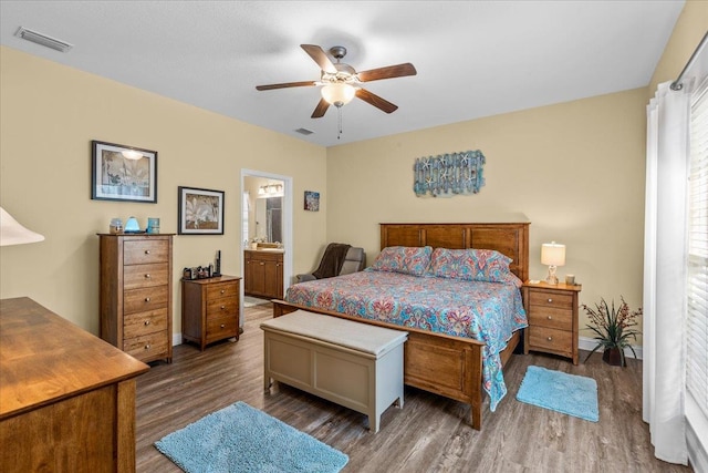 bedroom with wood-type flooring, connected bathroom, and ceiling fan