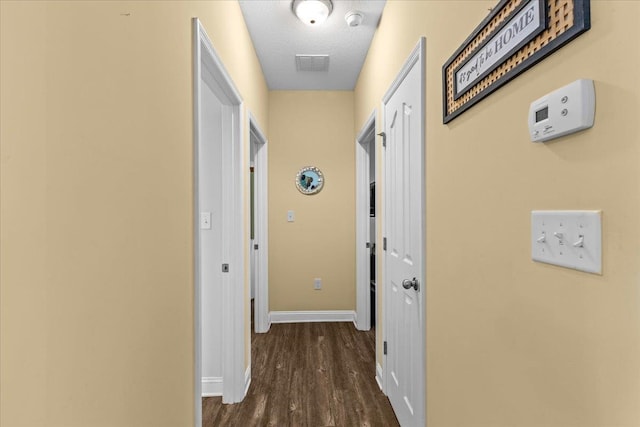 corridor with a textured ceiling and dark wood-type flooring