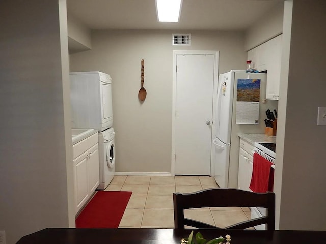 kitchen featuring range, white cabinetry, light tile patterned floors, and stacked washer and clothes dryer