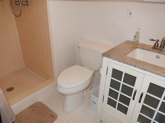 bathroom featuring vanity, tile patterned floors, toilet, tile walls, and a tile shower