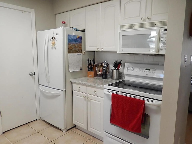 kitchen with light tile patterned floors, white appliances, white cabinetry, and backsplash