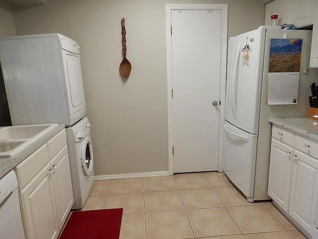 laundry room featuring stacked washer and clothes dryer and light tile patterned flooring