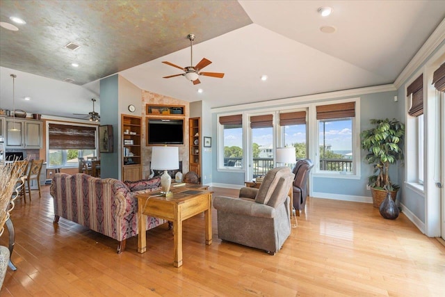 living room featuring a healthy amount of sunlight, light wood-type flooring, and vaulted ceiling