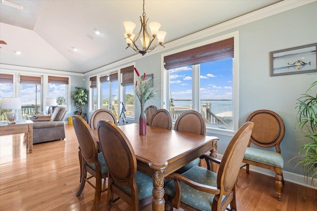 dining space with a chandelier, ornamental molding, light hardwood / wood-style floors, and lofted ceiling