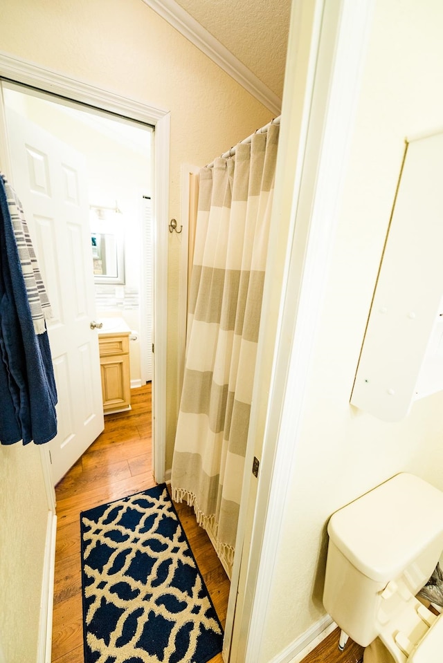 bathroom with a textured ceiling, hardwood / wood-style flooring, ornamental molding, vanity, and a shower with shower curtain