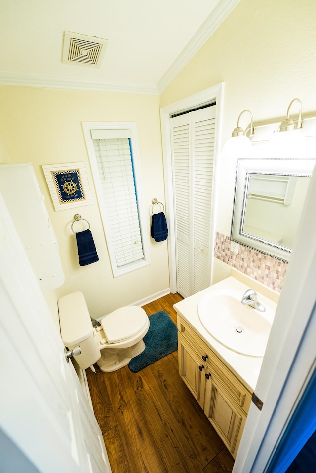 bathroom featuring lofted ceiling, toilet, hardwood / wood-style flooring, ornamental molding, and vanity