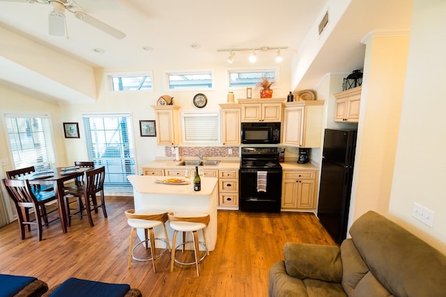 kitchen with black appliances, backsplash, dark hardwood / wood-style flooring, sink, and a breakfast bar