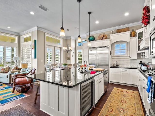45 Walker Creek Dr, Shell Point, FL 32327 - kitchen featuring beverage cooler, ornamental molding, white cabinetry, a center island with sink, and dark wood-style floors