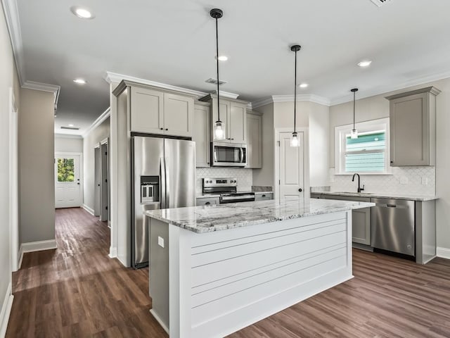 kitchen featuring dark wood-type flooring, a kitchen island, appliances with stainless steel finishes, and ornamental molding