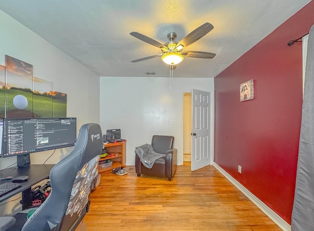 office area featuring light wood-type flooring, visible vents, baseboards, and a ceiling fan