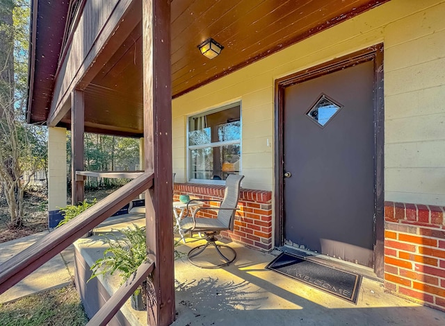 property entrance with covered porch and brick siding