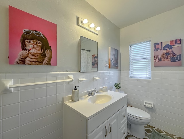 bathroom with toilet, a wainscoted wall, tile walls, and vanity