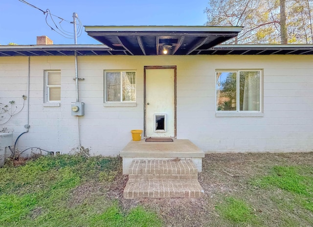 doorway to property with a chimney and concrete block siding