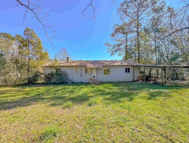 back of house with a lawn and stucco siding