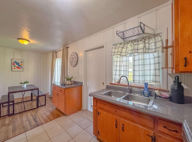 kitchen with light tile patterned floors, a decorative wall, a sink, and brown cabinets