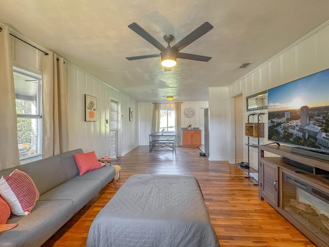 living area with a ceiling fan, light wood-type flooring, and visible vents