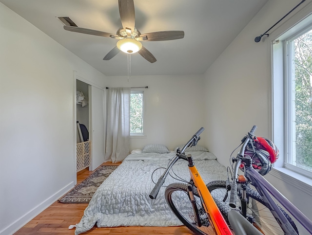 bedroom featuring multiple windows, ceiling fan, baseboards, and wood finished floors