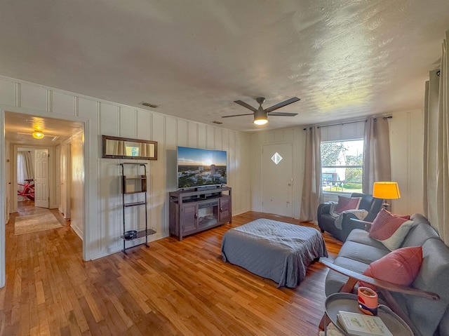 bedroom with visible vents, a decorative wall, light wood-style flooring, and ceiling fan