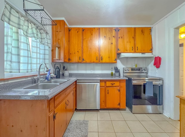 kitchen with under cabinet range hood, appliances with stainless steel finishes, brown cabinets, and a sink