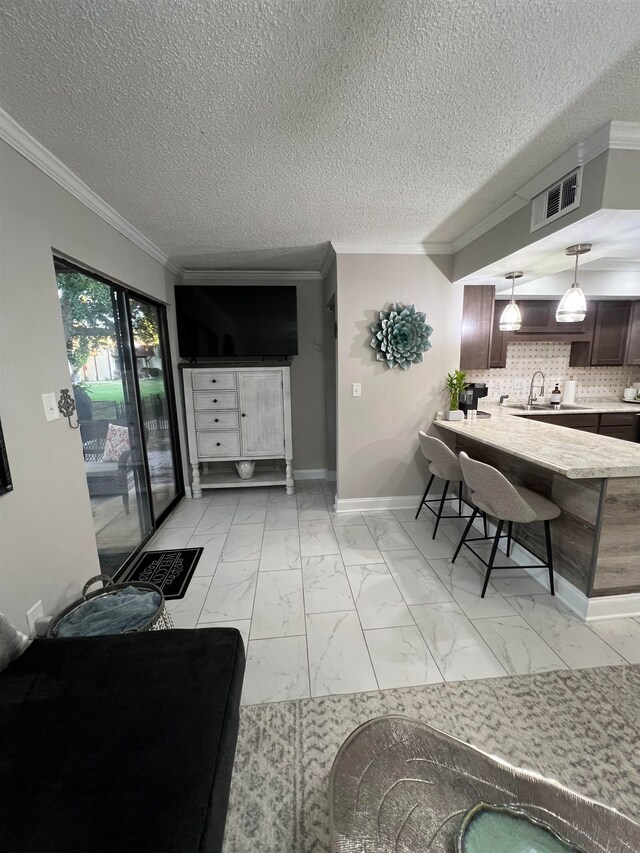 living room featuring a textured ceiling, sink, and crown molding