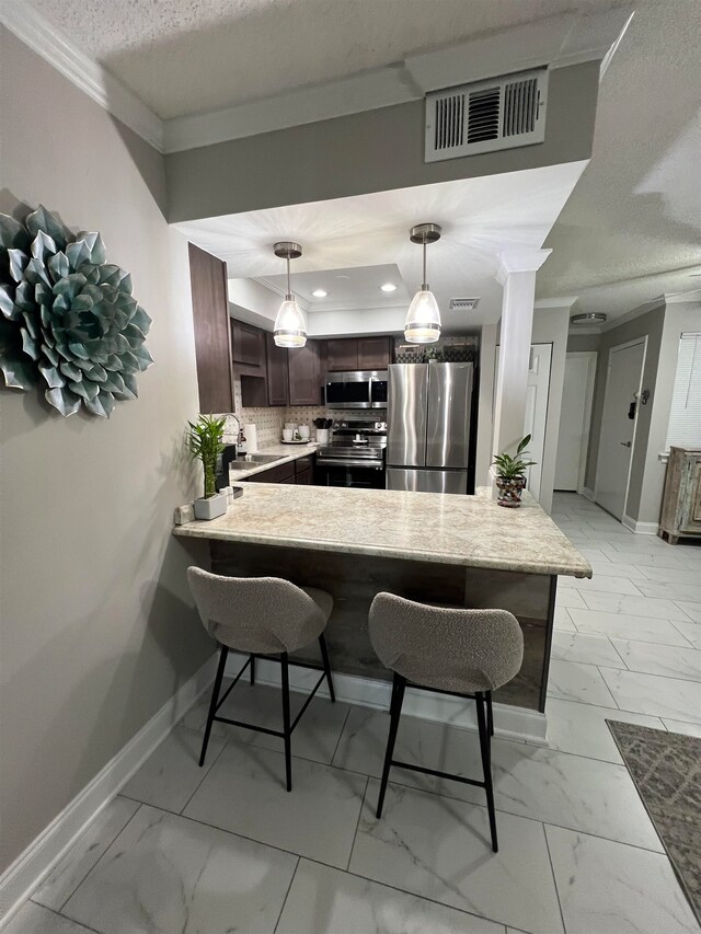 kitchen featuring stainless steel appliances, kitchen peninsula, a kitchen breakfast bar, pendant lighting, and decorative backsplash