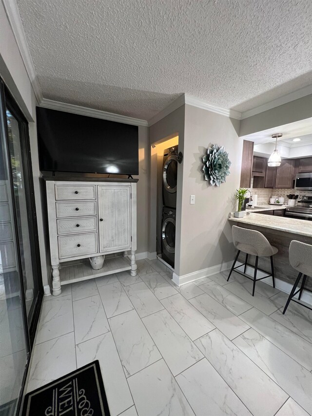 interior space featuring sink, stacked washer and clothes dryer, a textured ceiling, and ornamental molding