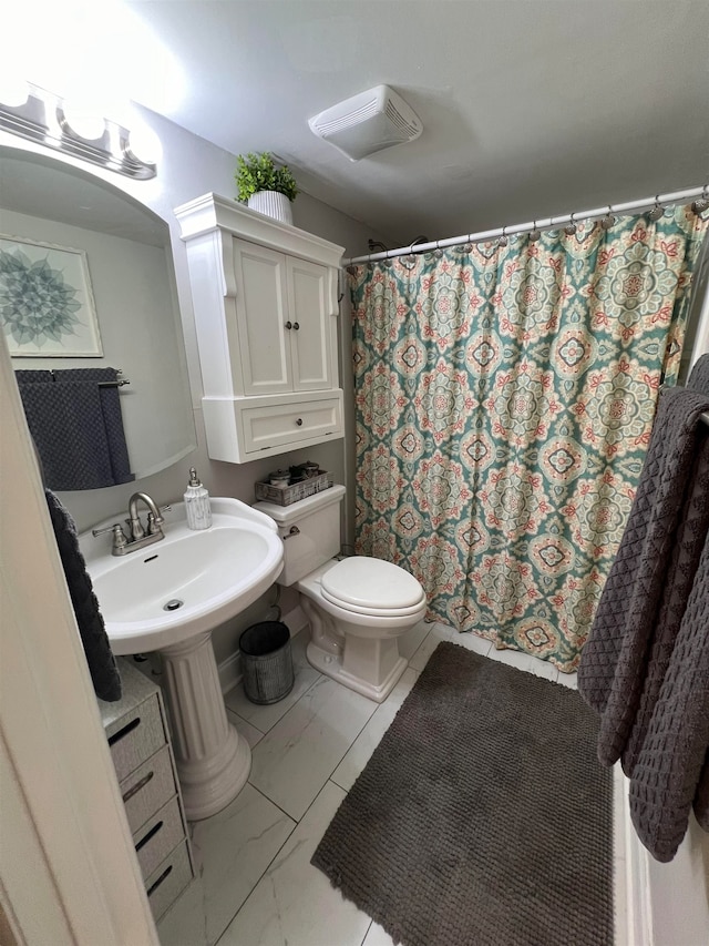 bathroom featuring curtained shower, sink, and toilet