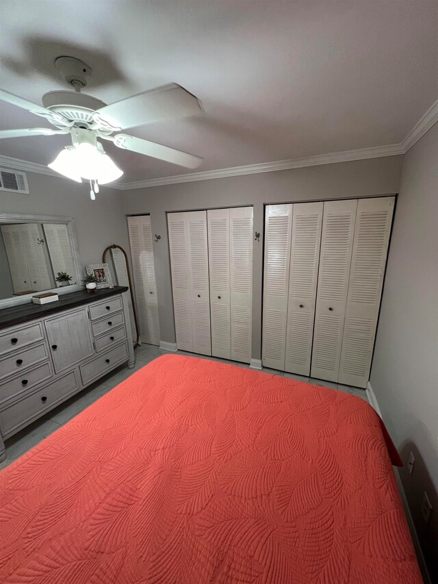 unfurnished bedroom featuring ceiling fan, two closets, and ornamental molding