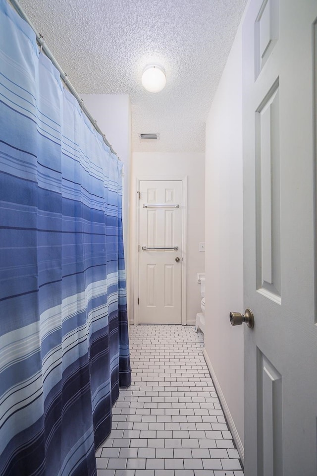 bathroom with tile patterned flooring and a textured ceiling