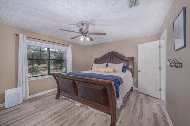 bedroom with ceiling fan, light hardwood / wood-style flooring, and a textured ceiling