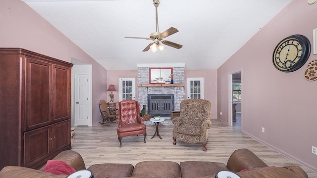 living room featuring a fireplace, light hardwood / wood-style floors, vaulted ceiling, and ceiling fan